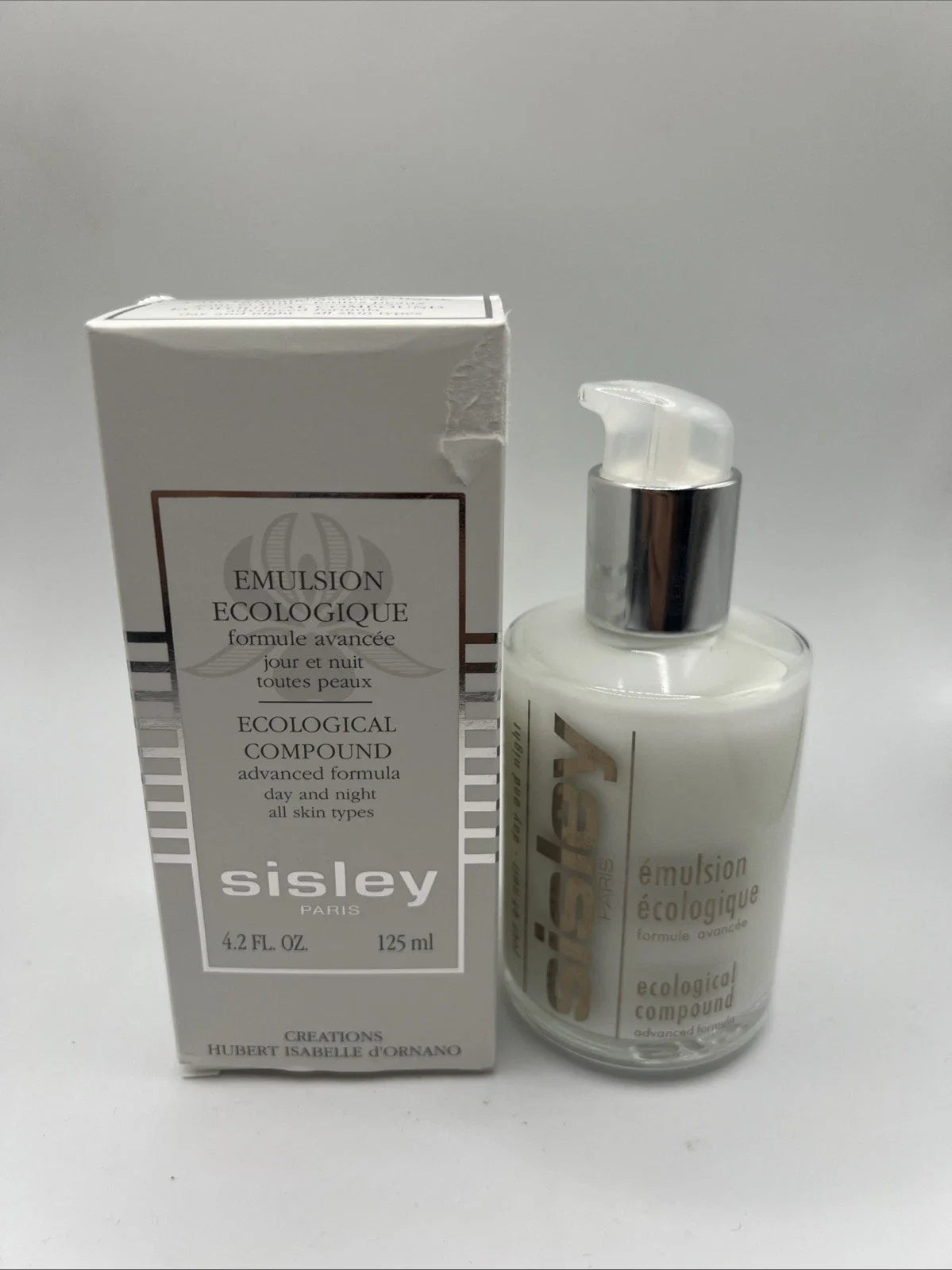 Sisley Emulsion Ecologique emulsion bottle with pump next to its original white packaging box, on a neutral light gray background.